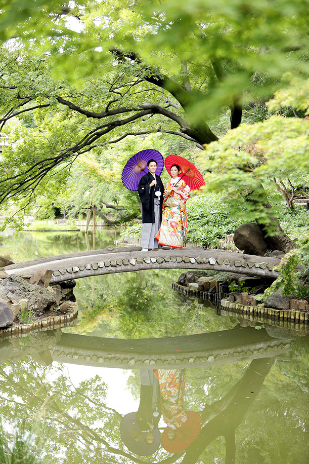 肥後細川庭園にかかる橋の上で和傘を持ちポーズをとる新郎新婦