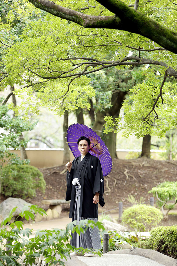 肥後細川庭園にかかる橋の上で和傘を持ちポーズをとる新郎