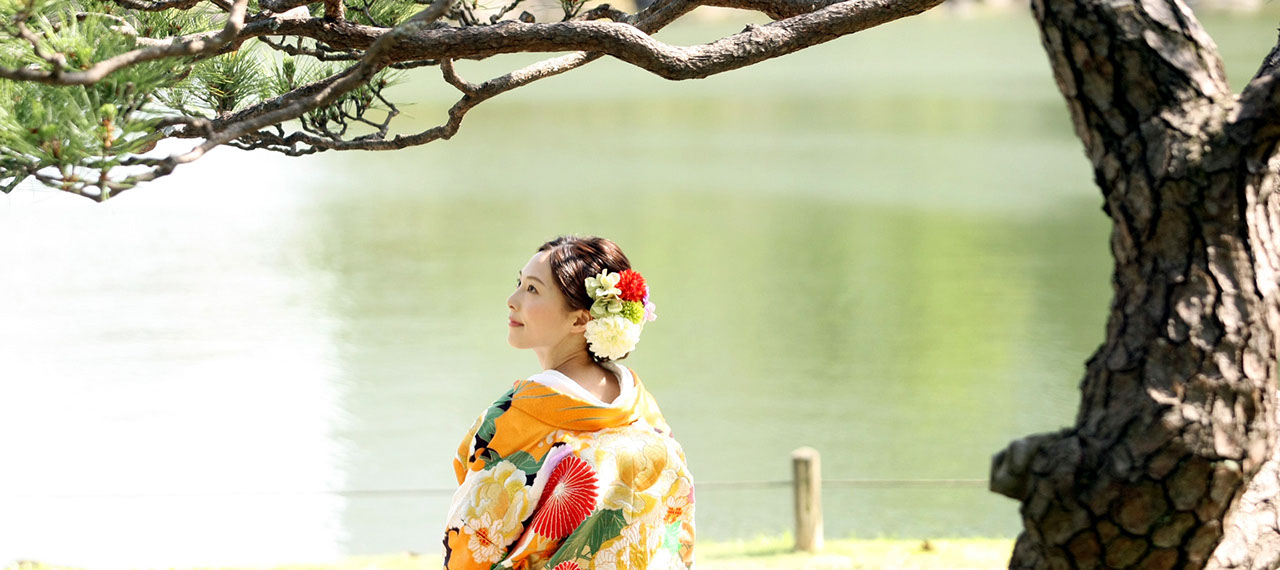 日本庭園を背景に松の下で微笑む新婦