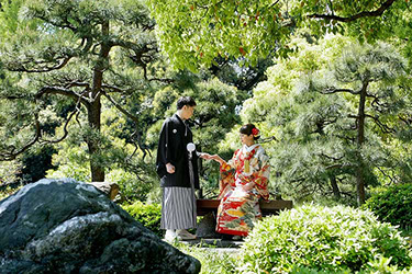 清澄庭園の松の前で手を取り合う和装新郎新婦