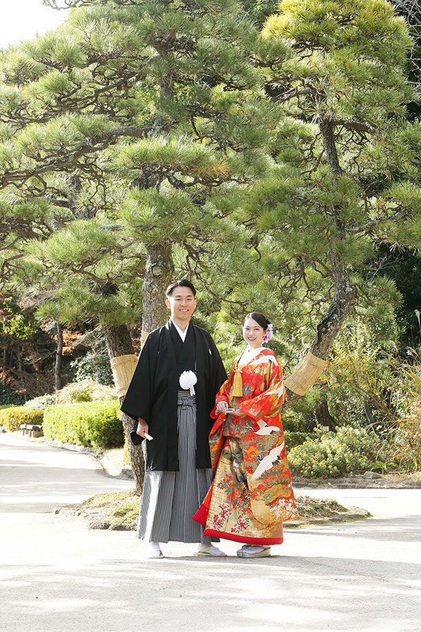 肥後細川庭園にかかる橋の上で和傘を持ちポーズをとる新郎新婦