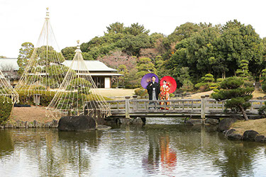 肥後細川庭園にかかる橋の上で和傘を持ち微笑む新婦