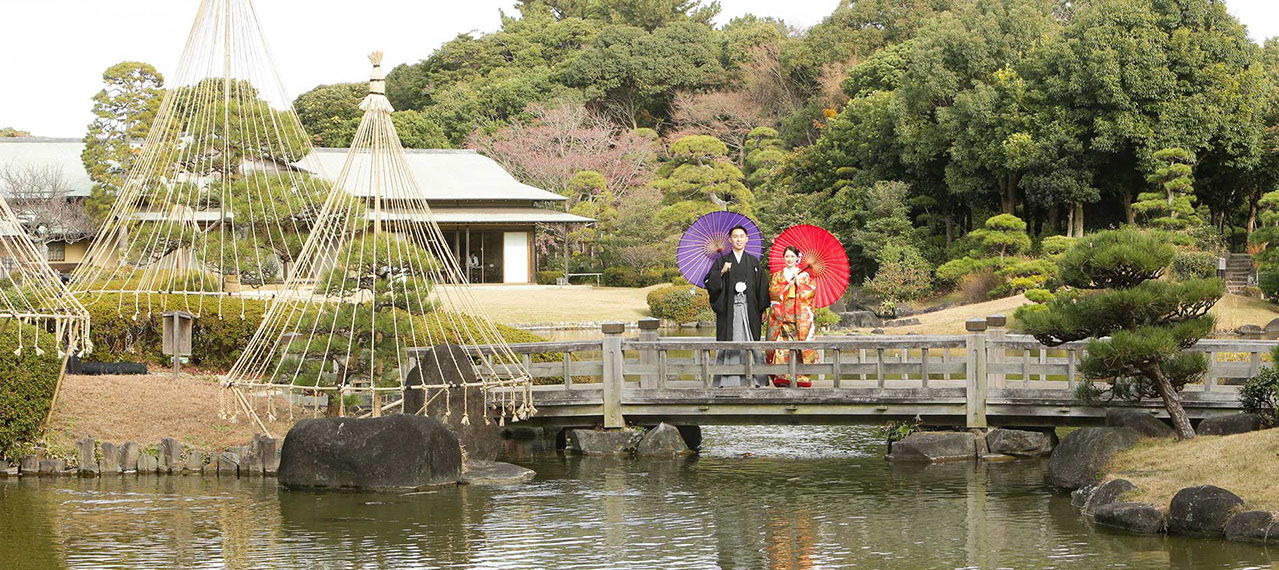 肥後細川庭園にかかる橋の上で和傘を持ち微笑む新婦