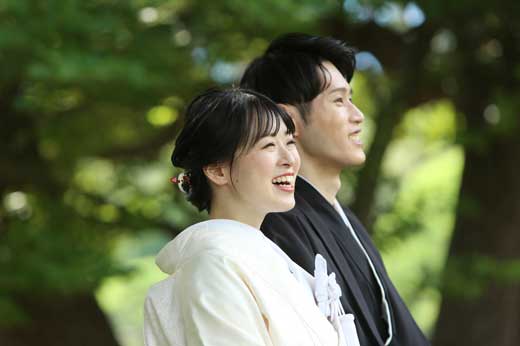 池のほとりの浮見堂でカメラを向きポーズをとる新郎新婦