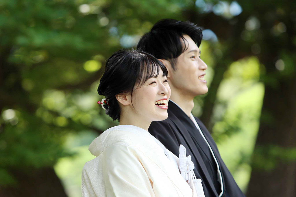 池のほとりの浮見堂でカメラを向きポーズをとる新郎新婦