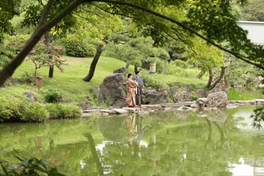 池を見つめ微笑む新郎新婦