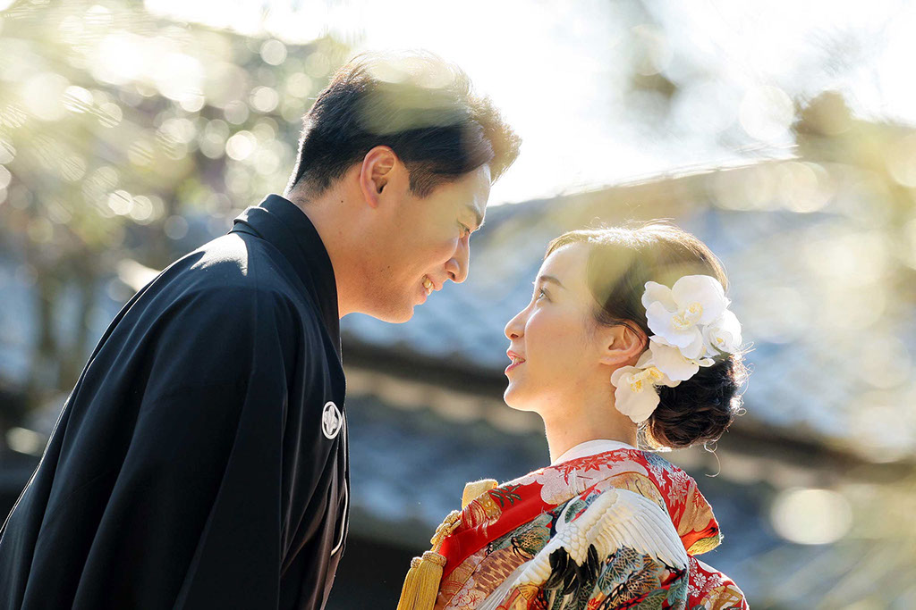 キラキラとした逆光の中見つめ合う和装姿の新郎新婦