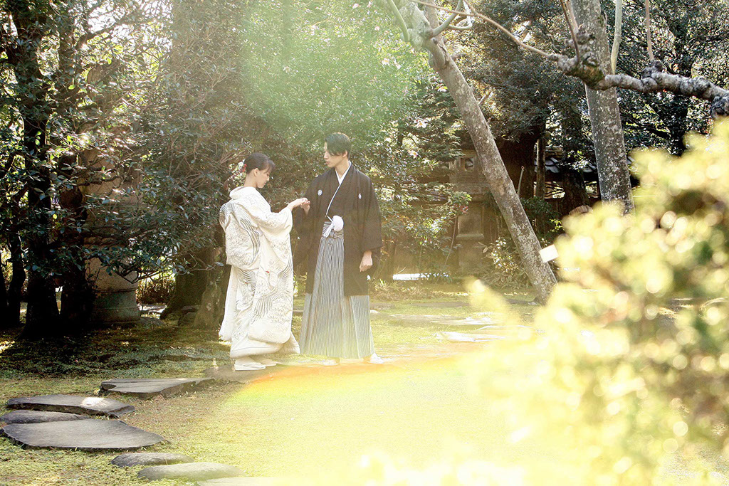 K邸の庭先で手を取り合い歩く和装姿の新郎新婦