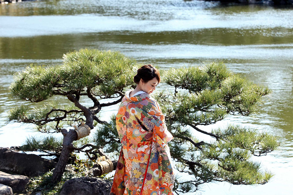 日本庭園の松の前でポーズをとる和装花嫁