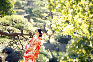 日本庭園の松の前で扇子を持ち微笑む和装花嫁