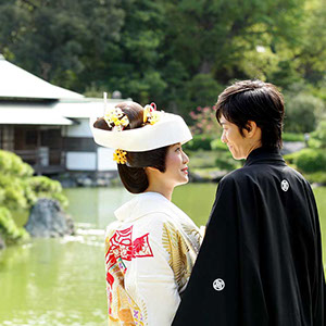 日本庭園の池のほとりで、愛を語り合う新郎新婦