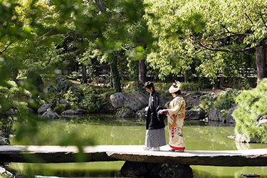 清澄庭園にかかる橋を手を引き歩く新郎新婦