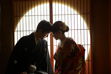 夏の光が差す障子を背景におでこを合わせる新郎新婦